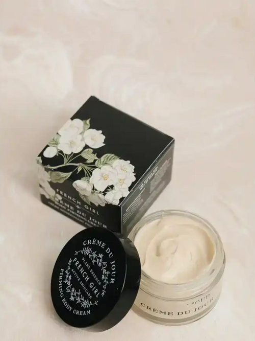 Minimalist flat lay of botanical skincare products including a jar of cream and black container on a neutral background.